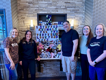 A group of staff members posing in front of a large White River Dental display filled with donated items and gifts.